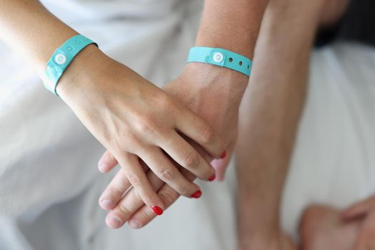 Male female hands holding hands with bracelets. Husband and wife or love couple together and hold each other hands