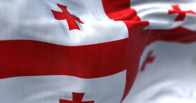 Close-up view of the Georgian national flag waving in the wind. Georgia is a country at the intersection of Eastern Europe and Western Asia. Fabric textured background. Selective focus