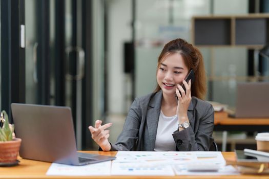 Young asian business woman smiling and talking on mobile phone.