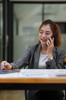 Young asian business woman smiling and talking on mobile phone.