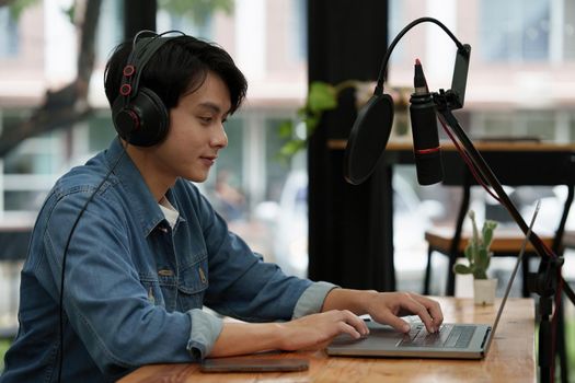 Podcaster editing audio podcast working at home studio.