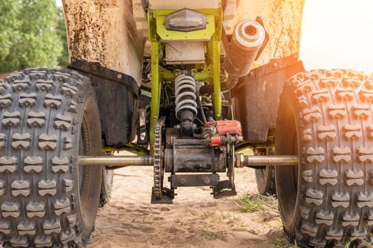 Rear view of the ATV standing on sandy ground. Wheels and suspension of the all-terrain vehicle. The concept of travel and adventure. shock absorbers, brakes, exhaust pipe, axles, chain, gear