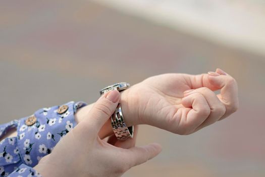 selective focus, beautiful bokeh. female hands. The female fastens her watch. woman puts on a watch. Wrist bracelet. woman fixing accessory. High quality photo