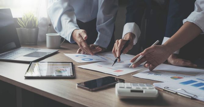 Closeup of businesspeople hands pointing a pie chart together on the paperwork.