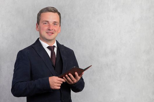 Smiling happy handsome man in a blue jacket on a white background with a digital tablet looks at the camera.