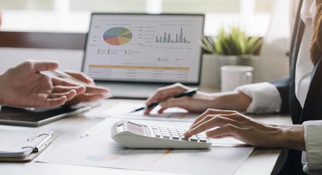 Close up Businessman and partner using calculator and laptop for calaulating finance, tax, accounting, statistics and analytic research concept.