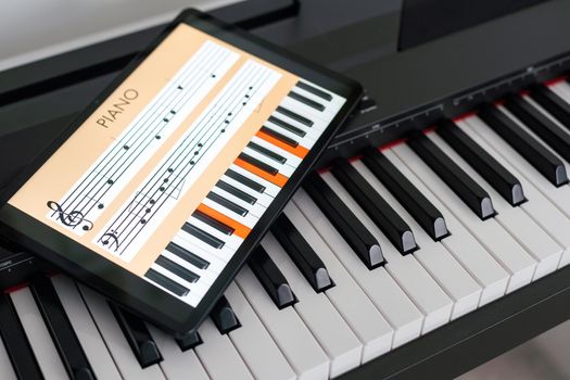 Piano synthesizer app on tablet and musical instrument concept.