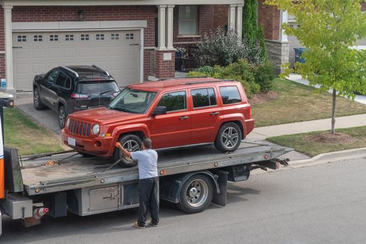 Emergency service driver attaches vehicle to carrier truck pad