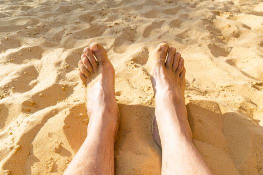 legs of a resting man on the sand close-up. photo