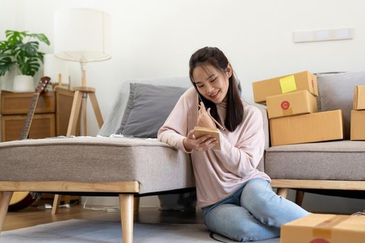 Young smiling beautiful owner asian woman freelancer sme business online shopping working on laptop computer with parcel box business online and delivery concept.