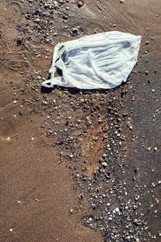 plastic bag polluting the beach, seashore and water pollution with plastics concept, waste at the seaside, top view of an environmental problem