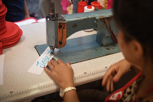 VERONA, ITALY - AUGUST 15, 2019: A woman embroiders a name on an old sewing machine. Souvenir from Juliet's house in Verona.