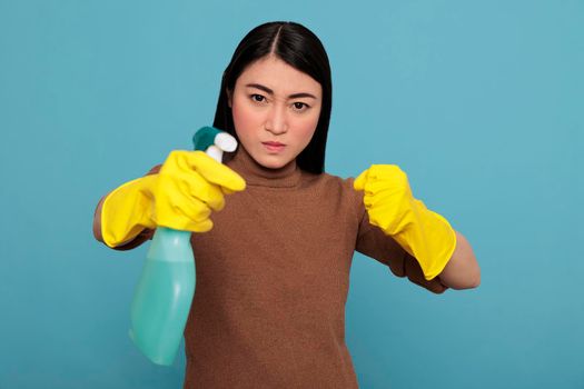 Aggressive overwhelmed asian young housemaid in rubber gloves and detergent spray standing in a fight pose, Cleaning home concept, Confidence energetic housekeeper feeling negative