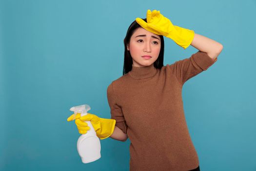 Young asian housewife stressed from daily work holding spray detergent in yellow rubber glove Cleaning home concept, Frustrated overwork housemaid with negative state of mind