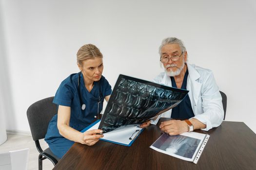 Team of doctors looking on results of X-Ray or MRI scan of patient's spine in medicine office