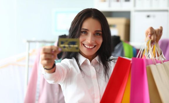 Portrait of woman holding shopping bags in store with bank credit card. Favorable shopping discounts and sales