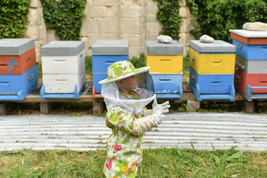A beekeeper child in apiary in a protective suit
