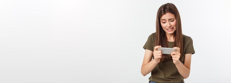 Happy attractive brunette girl joying win in video game on smartphone, isolated over grey background.