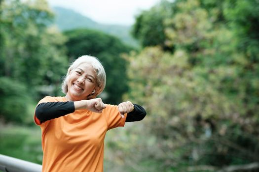 Happy athletic Senior woman in park before running in park, health concept.