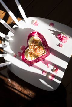 apple pie in the shape of a heart stands on a white chair in the rays of the sun shadow and light contrasting pattern homemade cakes for Valentine's Day, Mother's Day. High quality photo