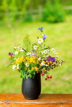 Still life in rustic style with a bouquet of wildflowers and strawberries