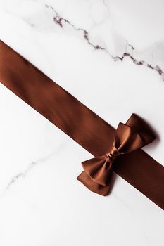 Holiday gift, decoration and sale promotion concept - Chocolate brown silk ribbon on marble background, flatlay