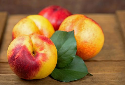 fresh nectarines with leaves on wooden background