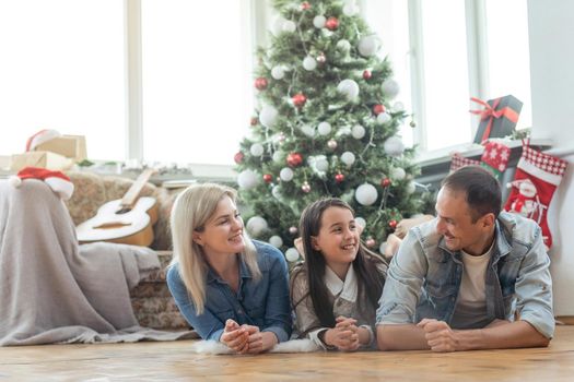family having fun and playing together near Christmas tree indoors