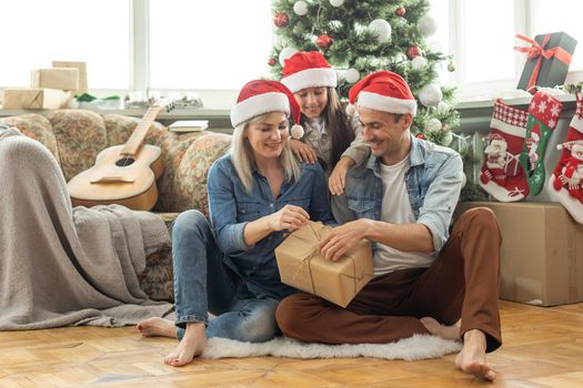 Christmas. Family. Happiness. dad, mom and daughter in Santa hats looking at camera and smiling