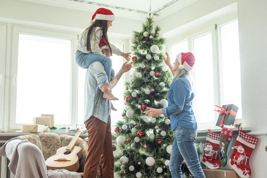 happy family mother, father and child daughter near Christmas tree at home.