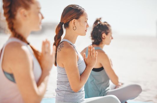 Women doing meditation class for wellness on beach, spiritual training exercise for calm and motivation for healthy lifestyle at the ocean in nature. Yoga group on summer travel holiday in Mexico.