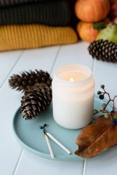 Hello fall. Cozy warm image. High angle view autumn composition with sweaters and candles, white candle mockup design