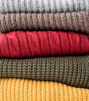 Hello fall. Cozy warm image. Stack of colorful autumn warm sweaters