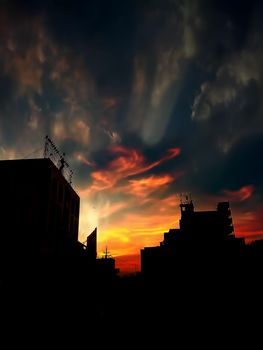 Sunset Dusk time shot of clouds and sun setting in background along with some silhouette of buildings also.