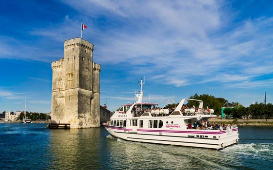 View of the entrance to the old port of the French city of La Rochelle with an incoming passenger ship and one of the towers in the background.