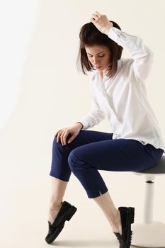 Woman in bad mood, bored and sad, sits on chair and puts hands on head. Woman in depression concept