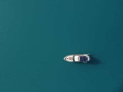 Aerial boat race. Luxury cruise trip. View from above of white boat on deep blue water. Aerial view of rich yacht sailing sea. Motor boat racing wave. Summer journey on luxury ship