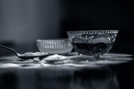 Baking soda face mask in a glass bowl on wooden surface along with baking soda powder and honey for Dark lips. Horizontal shot.