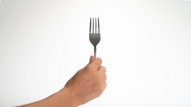 The hand holds the fork with its teeth up on a white background. High quality photo