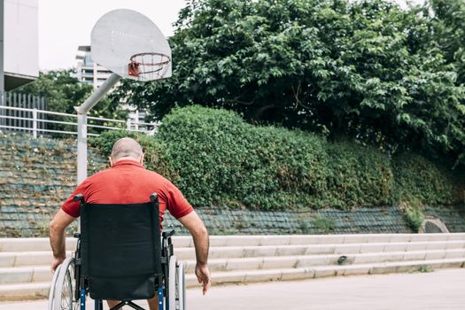 disabled man in wheelchair on the basketball court alone, concept of adaptive sports and physical activity, rehabilitation for people with physical disabilities