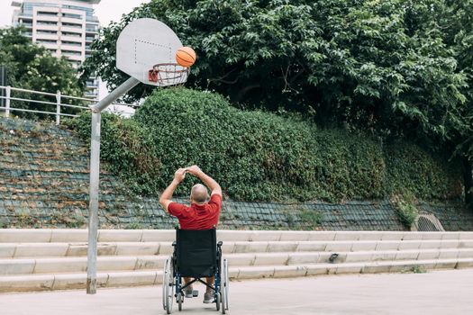 handicapped man playing basketball alone in the city, concept of adaptive sports and physical activity, rehabilitation for people with physical disabilities