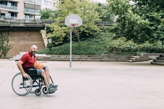 disabled man in wheelchair playing on basketball court alone, concept of adaptive sports and physical activity, rehabilitation for people with physical disabilities