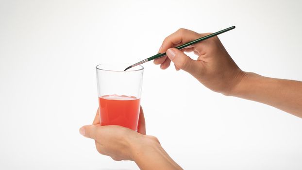 Women's hand cleans the brush from the paint in a glass of water