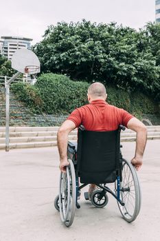 disabled man in wheelchair playing basketball on the court, concept of adaptive sports and physical activity, rehabilitation for people with physical disabilities, vertical photo