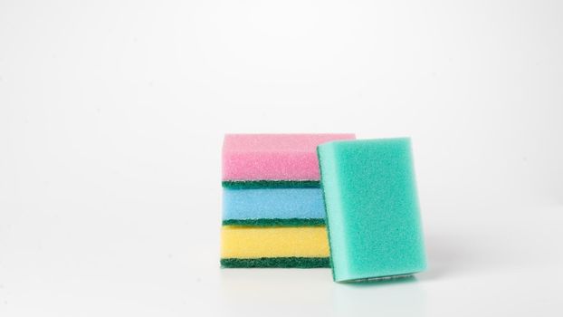 Sponges of different colors are stacked on a white background. High quality photo