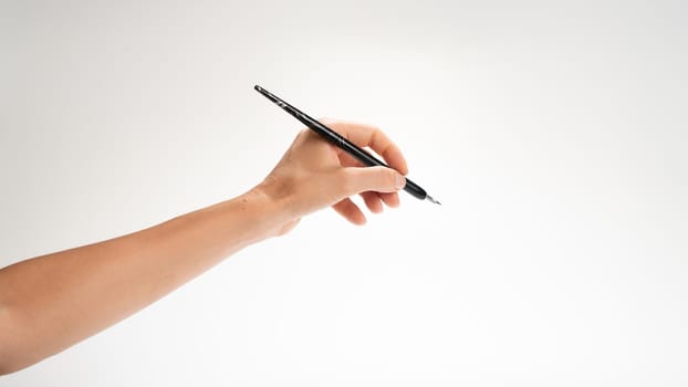 A woman's left hand holds a pen for calligraphy gesture writes. High quality photo