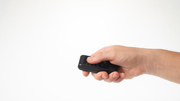 A man's hand holds a small remote control on a white background. High quality photo