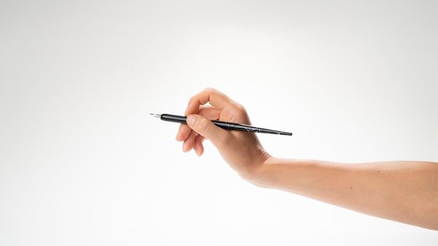A woman's right hand with a pen for fonts makes a gesture like writing. High quality photo