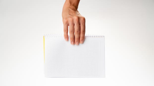 The hand holds the notebook in a cage descends from above on a white background. High quality photo
