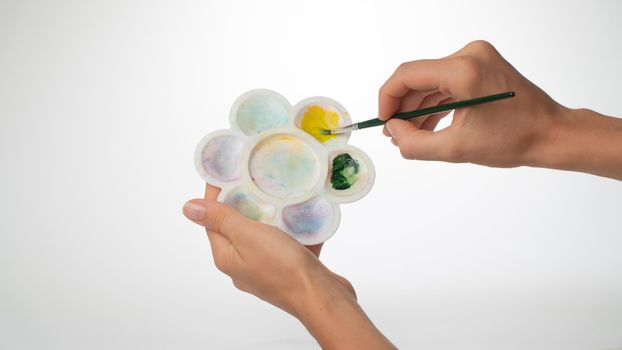 Women's hands with palette and brush, gesture to mix paint. High quality photo